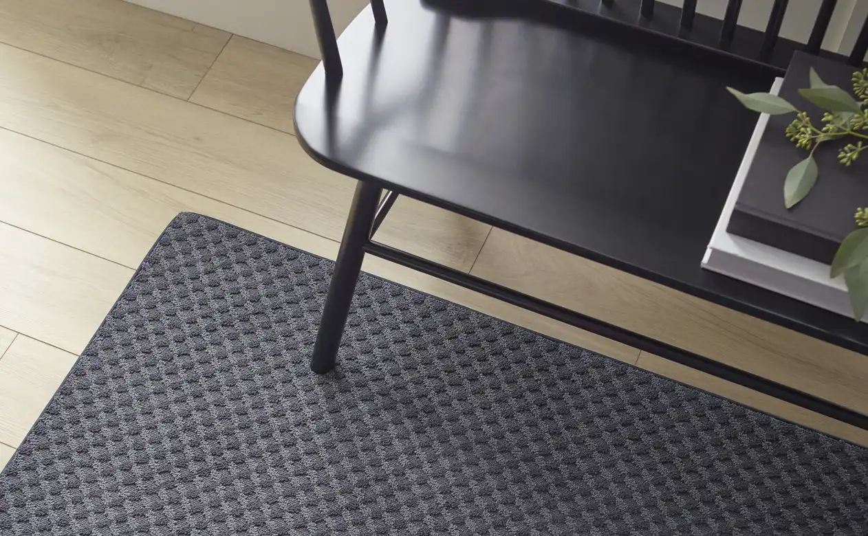 black textured area rug in entry way with black wood bench